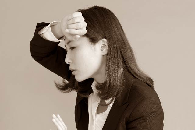 おでこを触る女性